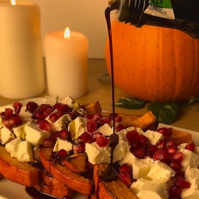 Pieczona dynia z fetą i granatem, polana olejem z pestek dyni.
